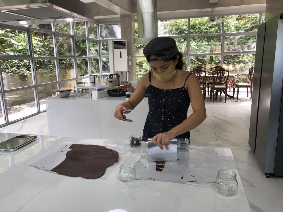 Alexa helping pour chocolate shards onto acrylic sheets in the commissary